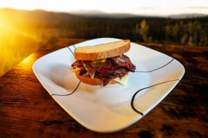 Picture of a smoked brisket sandwich with mustard and cheese on a white plate.